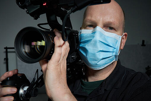 Dominic Borrelli mit medizinischem Mundschutz und Filmkamera